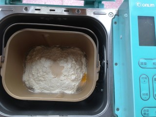 2、面包机版鸡蛋吐司,加入奶粉和面粉，在面粉顶端加入酵母，再将面包桶放入面包机里