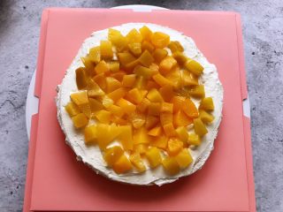 7、白雪公主蛋糕,用抹刀把淡奶油抹平,上面铺上一层黄桃