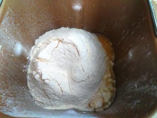 2、全蛋吐司,把面包粉、奶粉、酵母加入面包桶里。