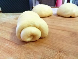 12、全蛋吐司,把面团反一下面，把面团擀成舌头状。将面团从上往下卷。