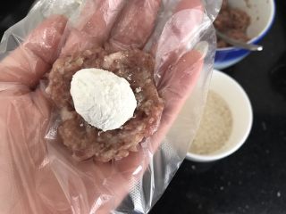 8、内有乾坤的肉丸子～苏格兰蛋,挖一勺肉末，手掌中间压平，把沾上面粉的鹌鹑蛋放在肉末中间