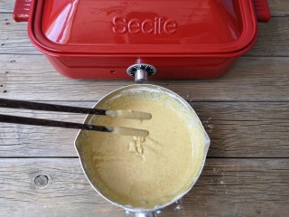 7、多啦a梦的铃铛烧,用筷子画“Z”字将粉糊搅拌至无颗粒状，用筷子提起粉糊落下呈缎带状。（加入牛奶的量可根据所用面粉吸水率不同来增减，主要还是看最后调好的粉糊状态）