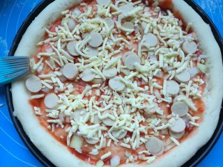 11、果干鸡肉披萨,刷上披萨酱,洒上几粒小香肠,撒一层马苏里拉芝士碎。