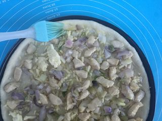 12、果干鸡肉披萨,把炒熟的鸡肉铺在表面,四周刷上蛋液。