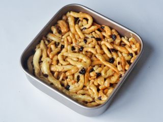 14、蔓越莓萨琪玛,将混合好糖浆的沙琪玛条快速倒入模具中，盖上油纸，使劲按压，尽量让其压紧，保证平整。