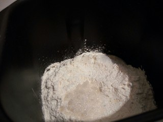 1、自制火腿肠披萨,先把面包机的桶拿出来，这样不会弄脏面包机内壁，饼底材料，除了黄油以外，先液体，再粉类（高筋面粉和低筋面粉提前过筛，混合均匀）依次放入面包机桶，盐和糖对角放，（酵母我提前和清水一起搅拌好了，放在最下面了）