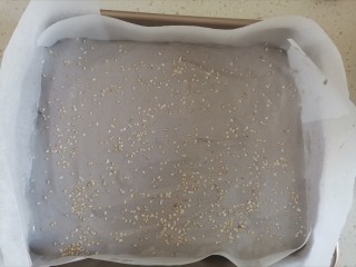 12、紫薯米粉蛋糕,倒入铺好油纸的烤盘里，撒上熟白芝麻