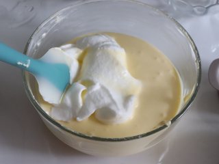 11、轻乳酪蛋糕（芝士蛋糕），醇香美味,取约1/3的蛋白，和蛋黄糊翻拌均匀，再倒入到蛋白盆中，继续翻拌均匀。