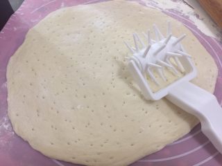 20、海陆双拼披萨,在案板上撒了面粉，取出面团擀圆，然后用滚针在面皮上滚一滚