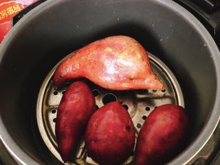 2、椰蓉薯圆,倒1盆水至电饭煲，放入蒸架，将地瓜放到蒸架上，按“煮饭”功能，将地瓜煮熟。