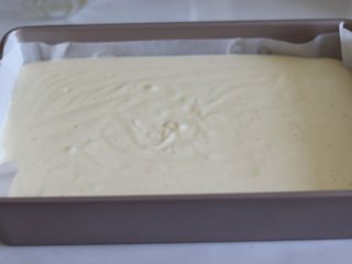 13、鲜橙方块大蛋糕,用刮板让蛋糕糊平整，轻轻震出大的气泡。