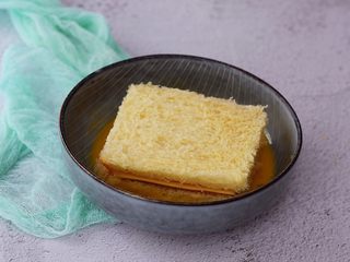 8、火腿西多士,把夹好芝士火腿的吐司放入蛋液中