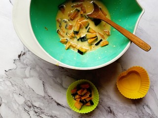 6、贝贝南瓜蒸蛋糕,取小模具，舀入南瓜丁和面糊