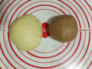 2、双色麻花吐司,分割成一大一小2个面团,小面团加可可粉揉匀。(用手沾温水揉更容易揉均匀)盖保鲜膜,发酵至2.5倍左右。