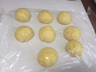 5、花朵豆沙面包,发酵至两倍大后，取出，分成等分的大小，一个大概是65克左右；排气，揉圆，盖上保鲜膜，醒15分钟；