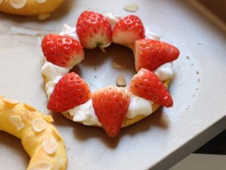 10、车轮泡芙,将泡芙对半剖开，圈上裱上奶油，依次放上对半切开的小草莓。草莓上也挤上奶油。