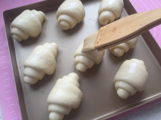 20、黄油面包卷,发酵25--30分钟，发到原来的1.5--2倍大时，烤箱开始预热上下火180度。这边给面团涂上蛋黄液。（要把多余的蛋黄液在碗边刮干净，这样涂上去才好看）