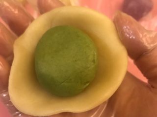 11、螺旋蛋黄酥,将每个油酥包入油皮中，收口捏紧，盖上保鲜膜松弛20分钟。