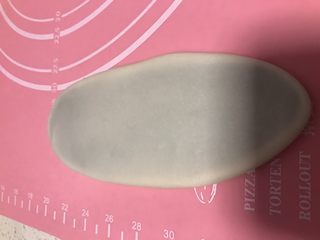 12、螺旋蛋黄酥,用手先稍微压扁，用擀面杖轻轻的擀成牛舌状，不要太用力，不然油皮容易破，擀大概18厘米长8厘米宽的样子，然后从上往下卷起来，盖上保鲜膜再松弛20分钟。松弛好后再次擀开卷起（手太油部分照片没拍）