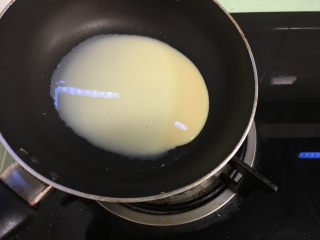 7、芒果千层蛋糕,根据自己平底锅的大小舀适量面糊,拿到燃气灶上,开小火,平底锅在火上转着将面糊摊匀.