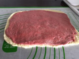 10、双色梅花吐司,把红色面团附在原色面团上擀开，稍微比原色小一圈。