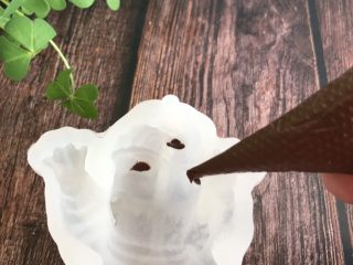 3、网红小狗慕斯蛋糕,在狗狗模具的眼睛和鼻子上挤上融化好的巧克力,然后放冰箱冷冻,冻硬