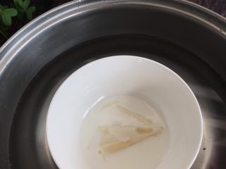 5、网红小狗慕斯蛋糕,把泡软的吉利丁片放入纯牛奶碗里,搅拌,隔热水融化