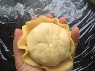 13、菠萝包,把压成薄饼状的菠萝皮轻轻移到手掌心，放入包了菠萝馅的面团、把边边的菠萝皮往面团里收一收即可。