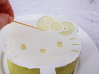 21、4寸KT猫抹茶慕斯蛋糕,再把白色的面片放在慕斯上，用牙签画出蝴蝶结、眼睛、鼻子、胡子的位置，再把巧克力按画好的位置摆放好即可