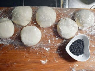 12、紫薯烧饼,将醒发好的面复揉成光滑的面团后，根据紫薯丸子的数量，将面团分成相同数量的面剂子，并准备适量的黑芝麻。