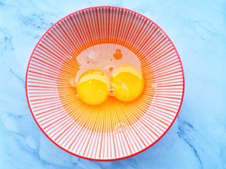 2、孜然火腿吐司丁,鸡蛋磕入碗中。