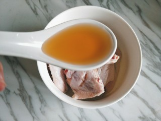 3、香酥炸鸡翅,放入一大勺料酒。