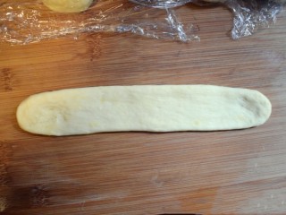 12、奶香葡萄干小面包（电饭锅版）,取一个面剂子，先戳成长条，再用擀面杖擀成裤带形的长条。