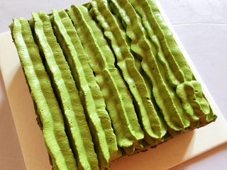 19、红豆抹茶巧克力慕斯,把冻过的慕斯取出,去掉围边后,用刀切掉四周的蛋糕边角料让四个边平整,再用花嘴挤上奶油装饰即可。