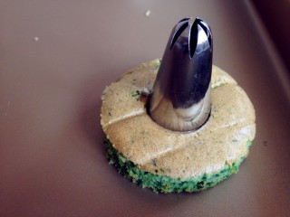 11、菠菜小蛋糕,蛋糕放凉后，用圆形模具压出12块蛋糕片，用花型模具压出三块蛋糕片，其中九块圆形蛋糕片用大号裱花嘴在中间压出圆形