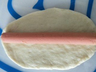 6、早餐＋火腿肉松面包,用擀面杖擀成长条，把火腿肠和肉松放在面片上