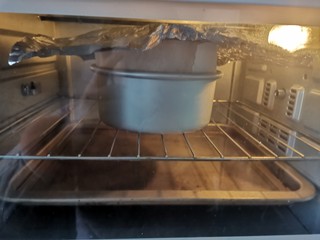 20、酸奶芝士蛋糕,送入预热好的烤箱，上下火160度烤60～70分钟，水浴法烘烤，蛋糕放中层烤网上，烤盘里加入3厘米的水放下层，蛋糕上色后盖锡纸