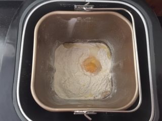 5、黑白小熊挤挤包,先将面包粉，糖，盐，酵母，牛奶和鸡蛋倒入面包机中启动揉面程序。