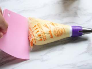 6、黄油曲奇,用刮板将面糊如图刮挤至花嘴口,将裱花袋中的空气排出。