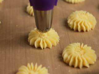 7、黄油曲奇,花嘴垂直于烤盘,与烤盘保持1cm距离挤曲奇,收尾时在中心点顺时针转一二圈,干脆利落提起花嘴。