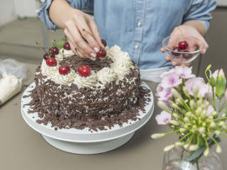 6、黑森林蛋糕,要完成蛋糕顶层，先在碗中加入剩余的奶油、塔塔粉和香草糖，搅打至硬性发泡，倒入带星型裱花嘴的裱花袋中。用生奶油涂满整个蛋糕，在侧面装饰上巧克力屑，也在顶部装饰上一圈巧克力，在边缘处均匀地裱上12个星型奶油花，在上面分别点缀一颗樱桃，冷藏2小时后就可以享用啦！