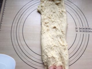 7、牛角包,把面团搬出面包桶。不要生拉硬拽，我用刮板把面团“托”出来的。之后在案板上进行“搓”面。怎么“搓”面，我是这样的手势：左手抓住面团底端，右手抓住面团上端，然后像洗衣服那样，右手抓着面团搓出去。然后再用刮板收回来，再重复“搓”面，搓6-8分钟左右。这时面团里面的面筋网络链在不断重新排列。