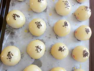 18、苏式月饼《蛋黄酥》,放入铺好油纸的烤盘，刷上蛋黃液，上面撒上黑芝麻