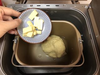 2、超简易吐司,将室温软化的黄油切小块放入面包机中继续揉面25分钟