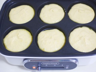 8、莲蓉馅南瓜椰蓉饼,放入多功能锅的模具中，底部撒少许椰蓉，先放一半面糊。