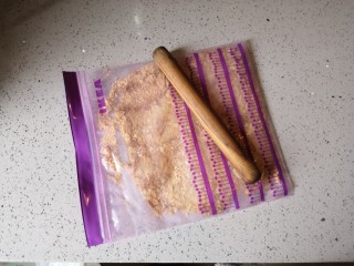 1、重芝士蛋糕,将消化饼干装入密封袋里用擀面杖压碎。