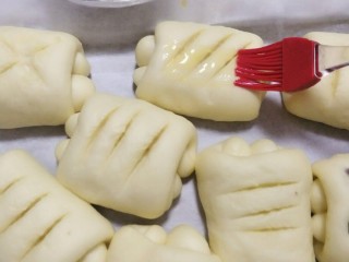 16、超级松软的萌面包,发酵好的面包拿出来用刀片割出花纹。刷层薄薄的蛋液。