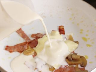 9、芝士意粉,将一杯牛奶和一片芝士和培根、口蘑混合,根据口味加少许盐。小火熬制浓稠,制成白汁。