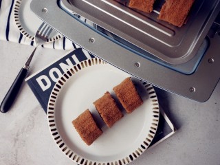 14、可可味小蛋糕卷,烘烤结束，把蛋糕取出，晾凉3分钟，再倒扣在另一张干净的油纸上