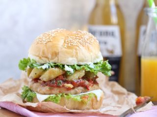 19、烤菠萝鸡肉汉堡,往汉堡胚上放入绿萝莎生菜叶、牛肉饼、鸡肉饼、烤菠萝、莎莎酱、芝士片。